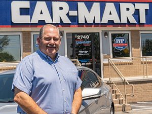Ted Taylor, Director of Expansion at Car-Mart, standing in front of a dealership