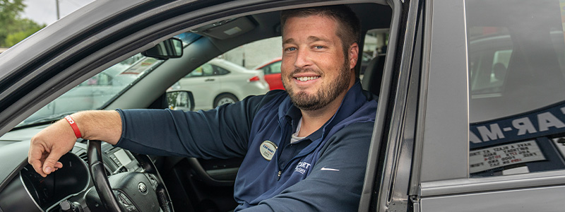 Zach Snow, Manager at Car-Mart of Centerton, sitting in a vehicle on his lot.