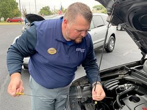 Bruce Lynch, Vice President of Inventory, checking the oil of a vehicle.