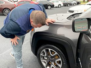 Bruce Lynch, Vice President of Inventory, checking the tires, brakes, and wheel well of a vehicle.