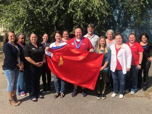 Kristina Carpenter with her team, holding her Wonder Woman cape.