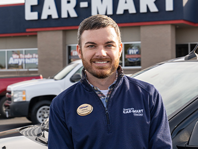Josh Meltzer, Director of Collection Services, in front of a Car-Mart dealership.