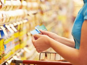 Woman shopping at grocery store using coupons