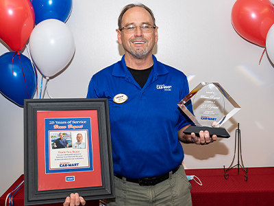 Bruce Bryant with his 25 years of service at Car-Mart award and poster