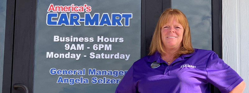Angela Selzer, General Manager at Car-Mart of Greenville, Texas, standing in front of building