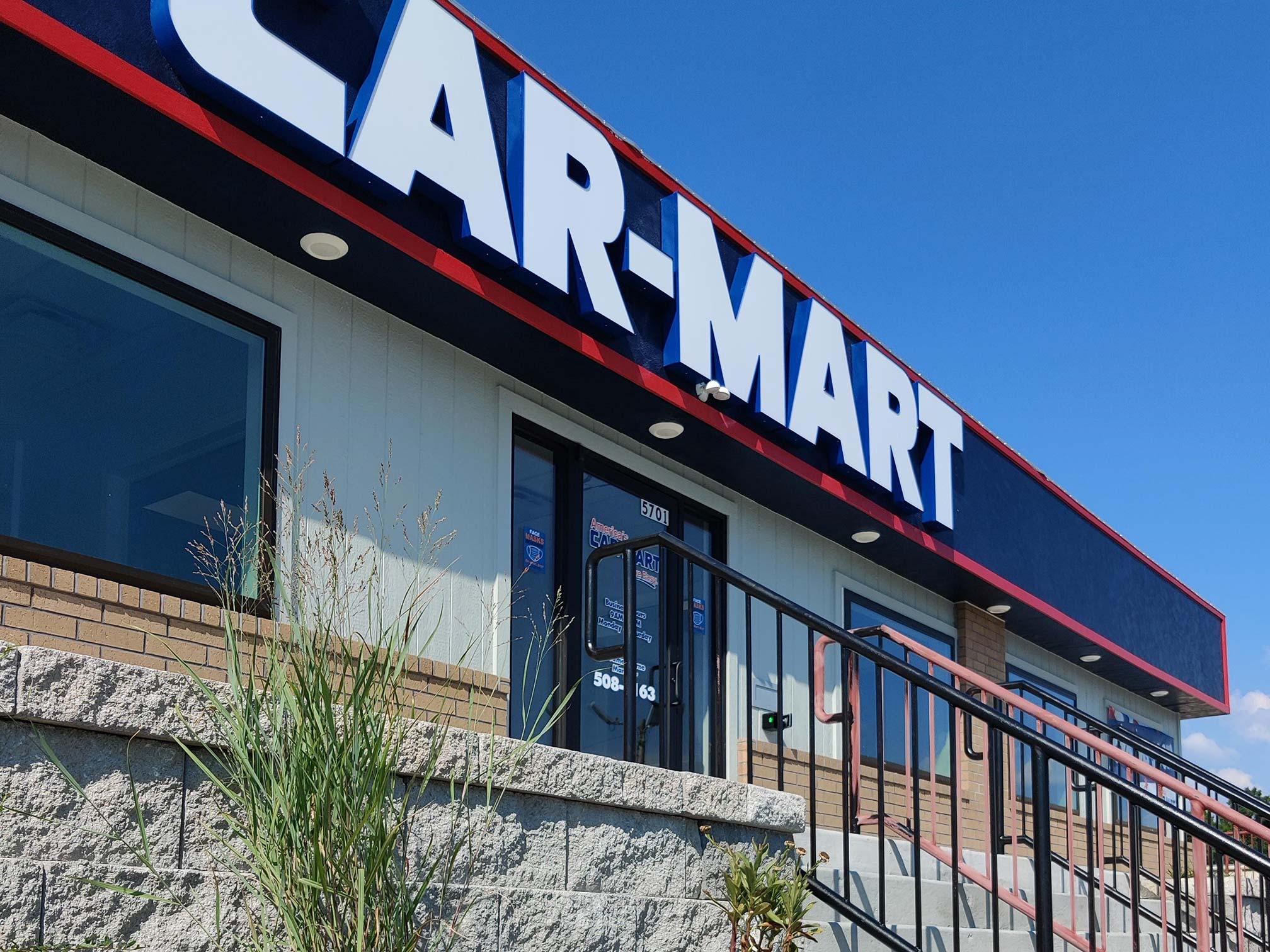 Low perspective view of stone and brick building with Car-Mart sign