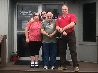 Keith, Dorothy, and their son standing with Dennis Hurley, GM at Car-Mart of Morrilton