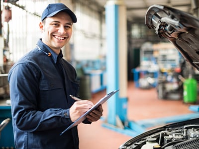 smiling mechanic inspecting vehicle