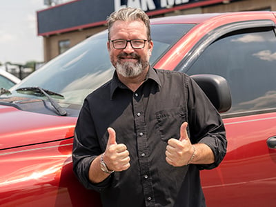 Customer Will Brown standing by his truck and giving two thumbs up at a Car-Mart dealership
