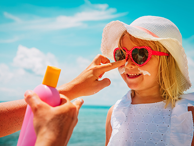 applying sunscreen to a smiling little girl face