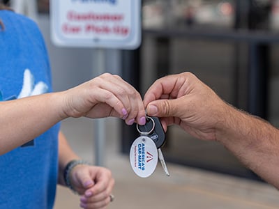 A Car-Mart sales associate handing the car keys to a customer.