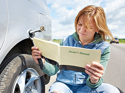 woman reading car owner's manual by the side of the road