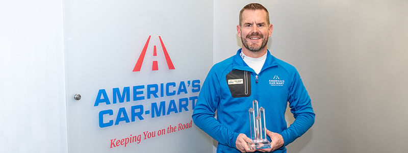 Curtis Valentine, General Manager at Car-Mart of Rogers, holding his Mentor of the Year Award