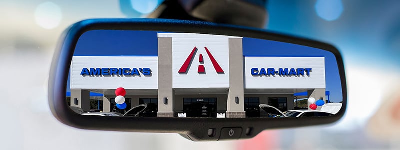 New Car-Mart dealership in the rearview mirror of a car