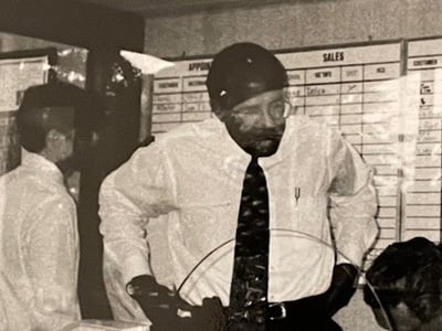 Doug's dad standing at the sales desk supervising his first sale