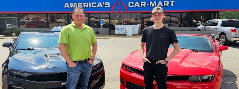David and Dawson Maples standing in front of the Camaros they purchased from Car-Mart of Benton, Ark.