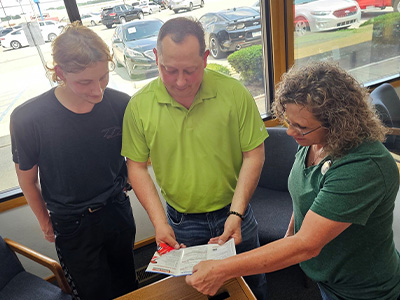 Marcey Poole, Assistant Manager at Car-Mart of Benton, going over the optional Service Contract with David and Dawson
