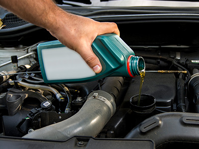 man adding oil to car engine