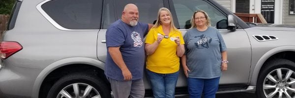 Customers Mike and Heidi Dudley with Car-Mart General Manager Pamela Turley stand by the Dudley's new car.