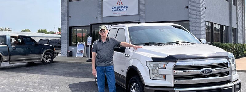 James Holland a customer at America’s Car-Mart of Rogers, Ark standing with his Ford truck