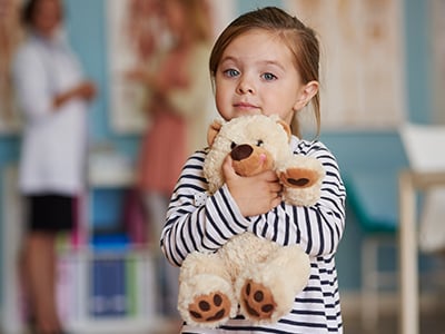 Little girl holding a teddy bear in the hospital.