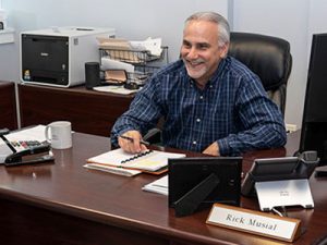 Rick Musial VP of Underwriting for America's Car-Mart sitting at desk smiling while working