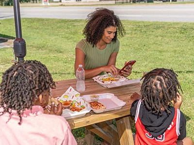 Woman applying for used car financing at a park with her children