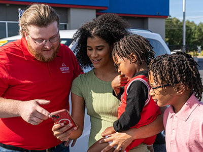 Woman with children showing a Car-Mart associate her phone with her pre-qualified financing amount