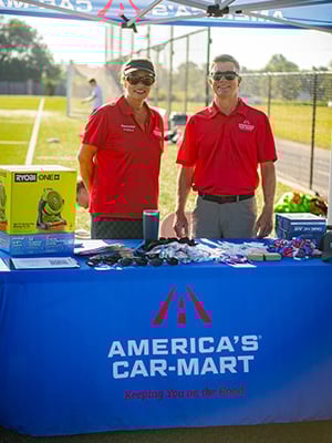 Two Car-Mart associates standing at youth soccer clinic booth and tent.