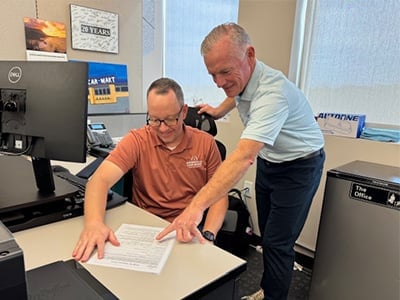 Senior Director of Remarketing at America’s Car-Mart, Doug Turner and Co-Worker looking at document